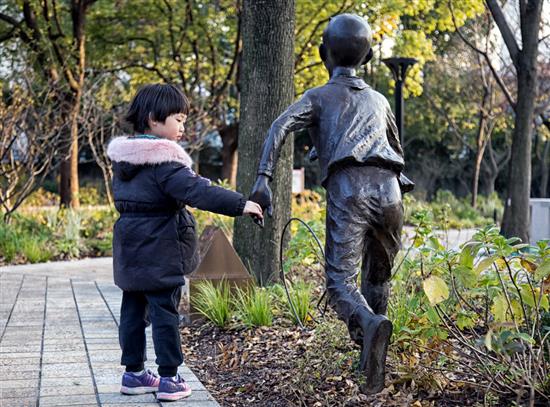 九子公园小孩与雕塑握手。
